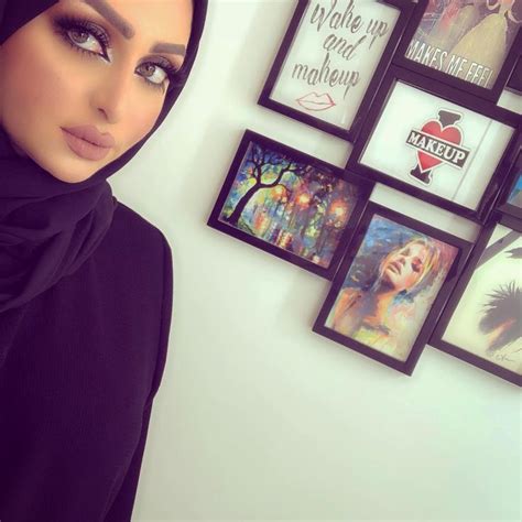 a woman wearing a hijab standing in front of pictures on the wall