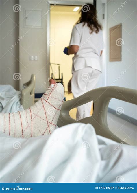 Man In Hospital Bed With Broken Leg Attended By Nurse Stock Image
