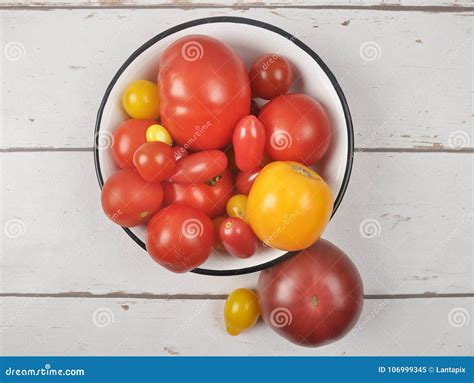 Variety Of Tomato Cultivars In Enamel Bowl On Weathered Wood Stock