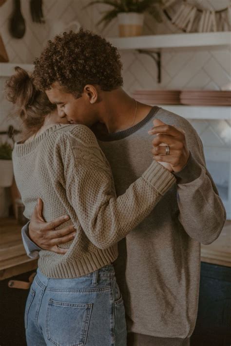 a man and woman hug in the kitchen while holding each other s arms together