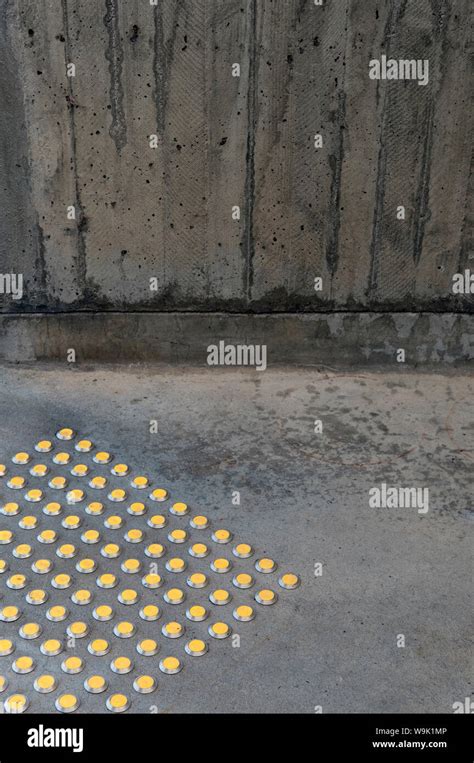 Yellow Tactile Pavement Warning Bumps Alongside A Brutalist Concrete