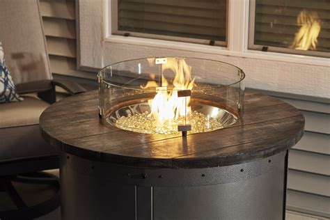 A gas fire pit table, in the simplest terms, is a portable propane gas tank connected to a burner in a concave bowl or basket in the middle of a very stylish table meant to provide warmth in your patio or backyard. Modern, industrial design Edison Round Gas Fire Pit Table with Glass Guard by The Outdoor ...