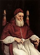 an old man with a long white beard wearing a red robe and sitting in a ...