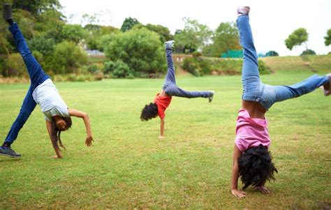 Premium Photo Cartwheel Fun Three Young Children Doing Handstands In