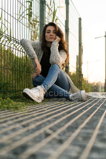 Woman Posing On Ground Near Fence — Outdoors Female Stock Photo