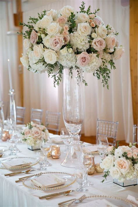 A Tall Vase Filled With White Flowers On Top Of A Table Covered In