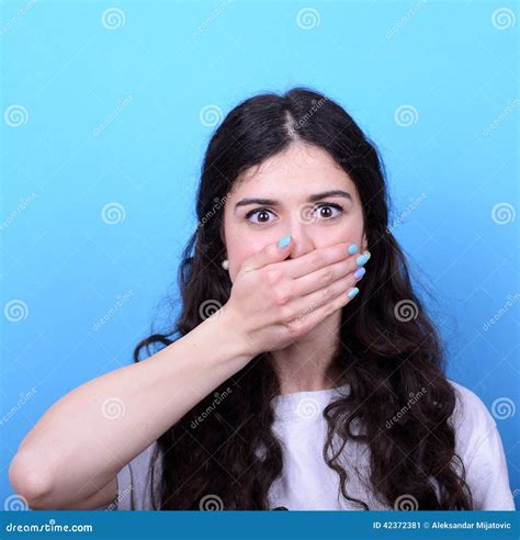 Portrait Of Girl Blushing With Hand Over Mouth Against Blue Back Stock