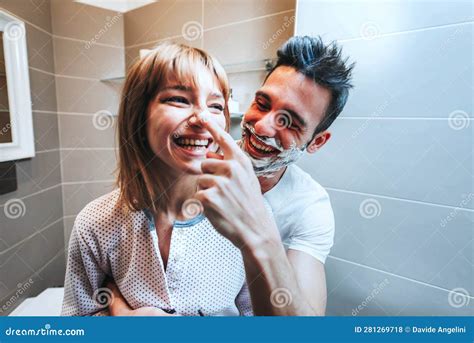 Husband And Wife Sharing Bathroom Together At Home Shaving Beard And