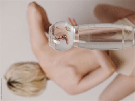 Nude Woman Reflecting Through Glass Of Water By Stocksy Contributor