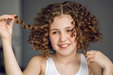 Close Up Portrait Girl Teenager With Curly Hair Playfully Holds Strands Of Hair With Her Hands