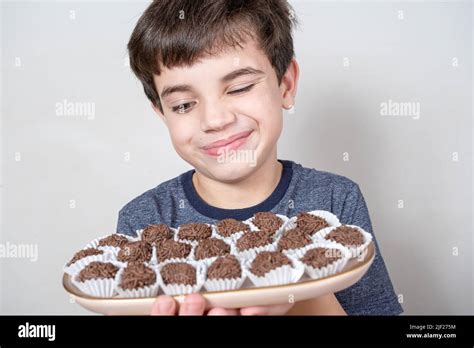9 year old looking at a tray with several brazilian fudge balls and with one eye closed stock