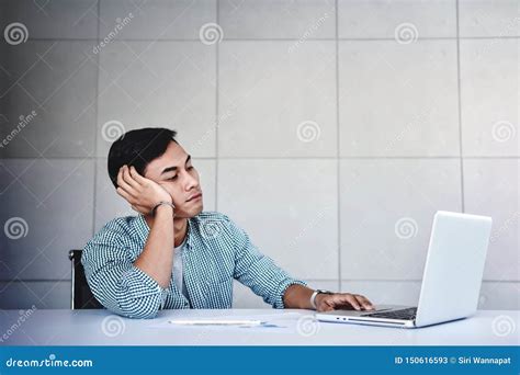 Tired And Stressed Young Businessman Sitting On Desk In Office With