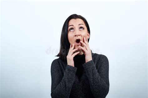 Shocked Woman Keeping Hand On Face With Opened Mouth Looking Up Stock