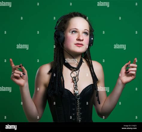 Sexy Gothic Woman With Dreads Wearing Bdsm Outfit Listening To The Music On Green Background