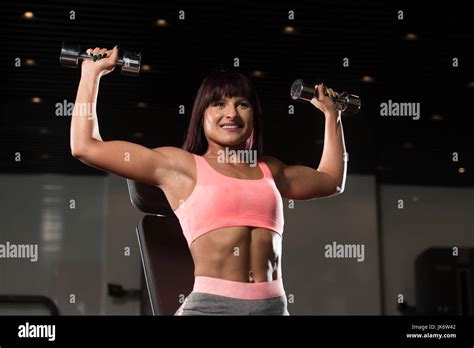 Woman Exercising Shoulders With Dumbbells In The Gym And Flexing