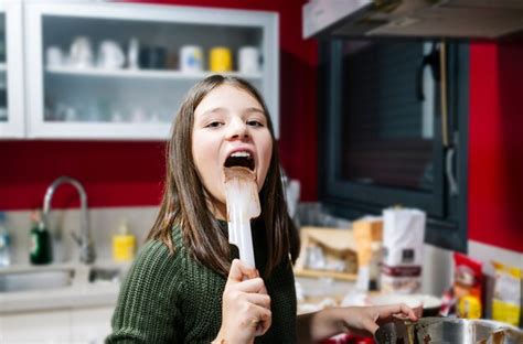 Uma Adolescente Chupa Os Dedos Manchados De Chocolate Em Sua Cozinha