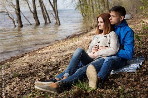 Young Couple Sitting On The River Bank Acheter Cette Photo Libre De