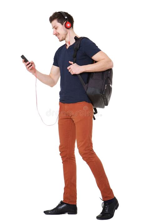 Young Man Walking With Mobile Phone And Listening To Music With