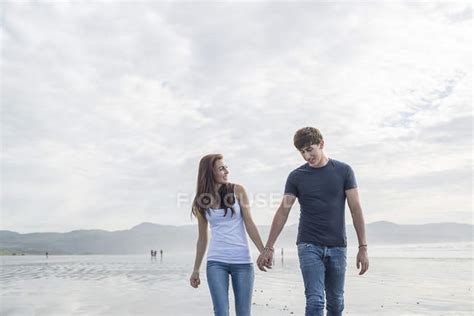 Couple Walk Holding Hands Across Beach Water Holiday Stock Photo