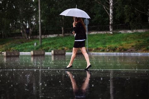 雨の中傘をさして歩く女の子 プレミアム写真