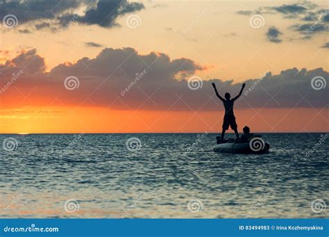 Silhouette Of Man Standing In A Boat On The Background Of Sunset Stock
