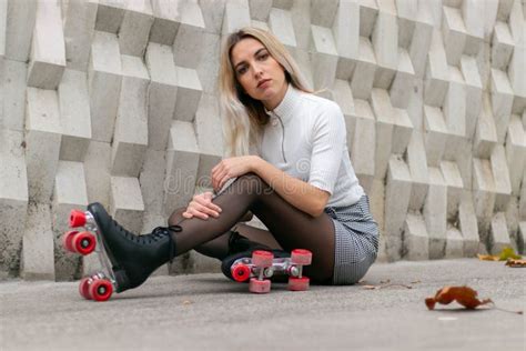 Blonde Girl Wearing A Skirt And Black Roller Skates With Red Wheels