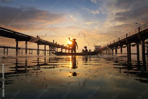 Stockfoto Silhouette Of Fishermen Using Nets To Catch Fish At The