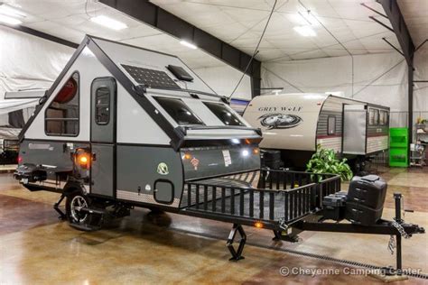 An Rv Parked In A Garage Next To Another Trailer