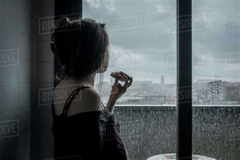 Woman Looking Through The Window In A Rainy Day While Eating Me