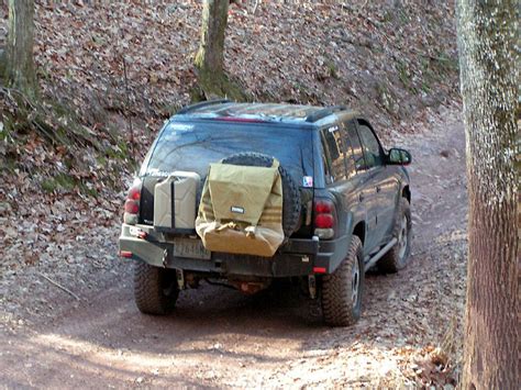 A Pick Up Truck Parked On A Dirt Road In The Woods With Luggage