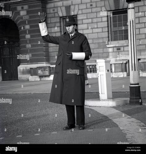 1960s Historical Picture Of A British Policeman Wearing Helmet Cape