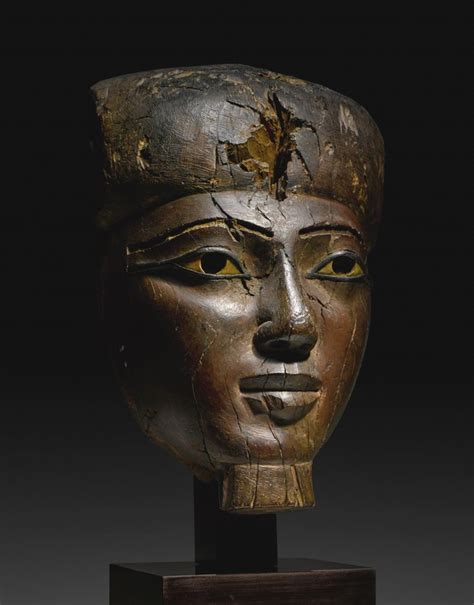 An Ancient Head Is Displayed On A Wooden Stand In Front Of A Black