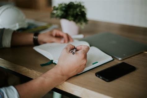 Person Taking Notes In A Notebook While Working From Home Stock Photo