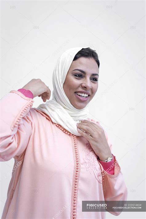 Smiling Moroccan Woman In Typical Arabic Dress Tying Hijab On White