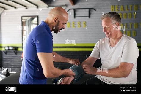 Male Health And Wellness Personal Trainer Assisting Elderly Senior Man