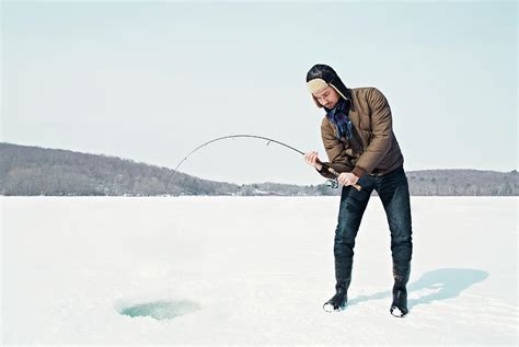 Man Ice Fishing On Frozen Lake By Andy Ryan