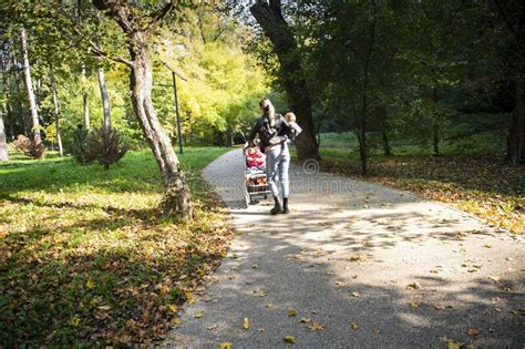 A Mother Is Walking Through The Park With Her Children Stock Photo