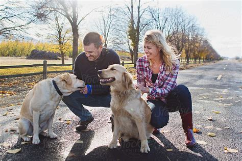 Couple Stops To Pet Dogs By Stocksy Contributor Tana Teel Stocksy