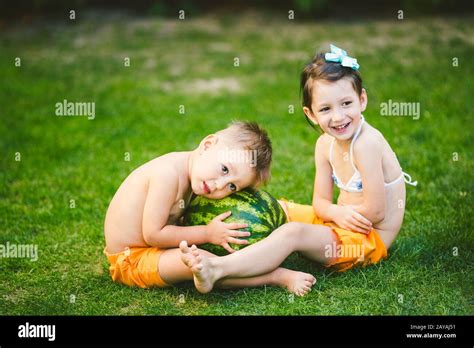 Two Children Caucasian Brother And Sister Sitting On Green Grass In