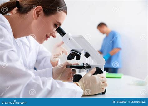 Scientist With Microscope And Colleagues In Laboratory Medical