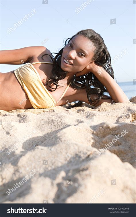 Attractive African American Woman Laying Down On A Golden Sand Beach By