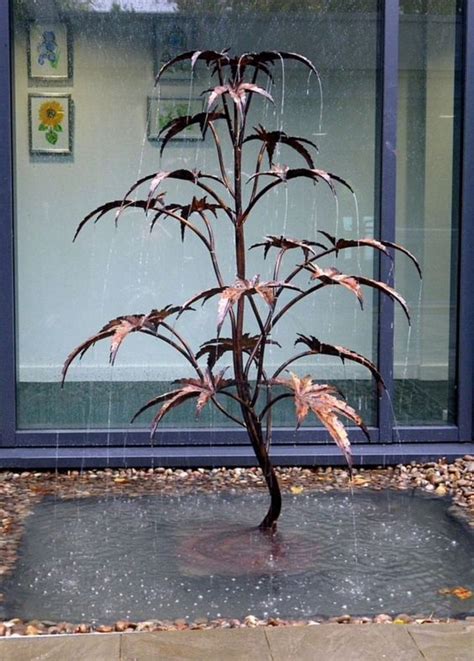 A Small Tree In Front Of A Window With Rain Falling On The Ground And