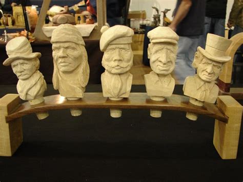 Five Carved Heads Are Sitting On A Wooden Bench