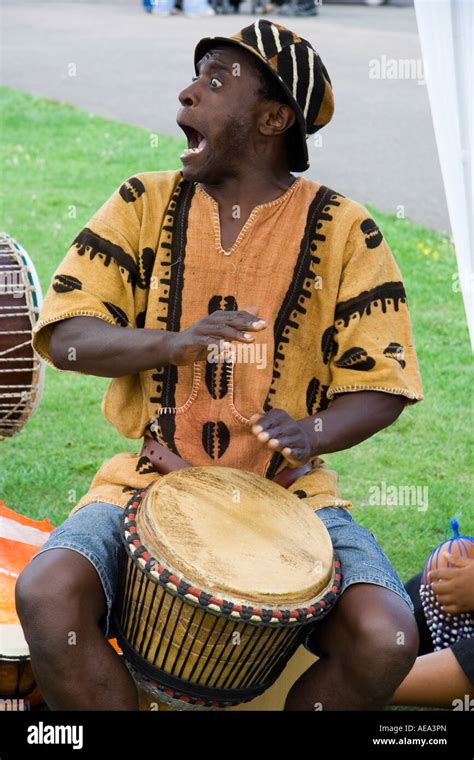 Black Jamaican Man Playing A Bongo Drum With Both Hands Facing The