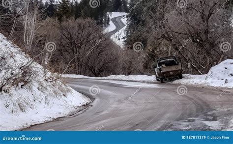 Panorama Road Winding Through Snowy Mountain With Leafless Trees And