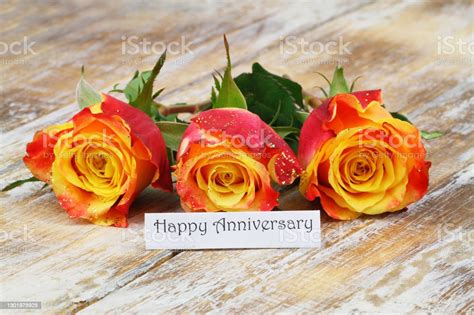 Happy Anniversary Card With Three Colorful Roses On Wooden Surface