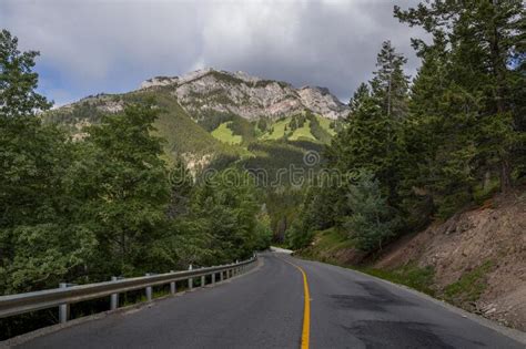 Curved Empty Country Road Passing Through Forest And Green Mountains In