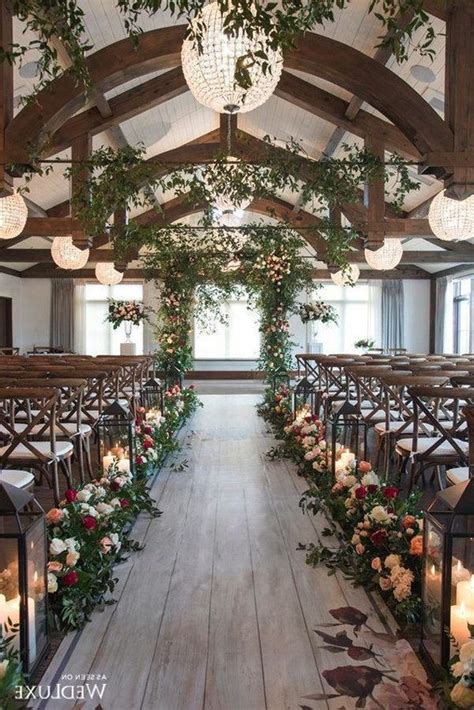 An Indoor Wedding Venue Decorated With Greenery And Flowers Candles
