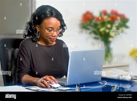 Jolie femme noire de taper sur son ordinateur portable dans son bureau à domicile Photo Stock