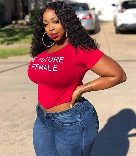 A Woman In A Red Shirt And Jeans Posing For The Camera With Her Hands On Her Hips